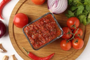 Lezzetli salsa sosu ve beyaz ahşap masa üzerindeki malzemeler.