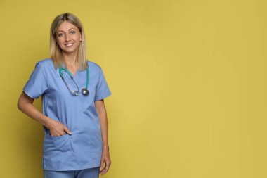 Sarı arka planda steteskoplu hemşire portresi, mesaj için yer