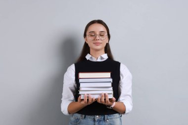 Gri arkaplan üzerine kitap yığını olan genç öğrenci