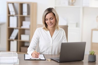 İş kadını ofiste notlar alıyor.