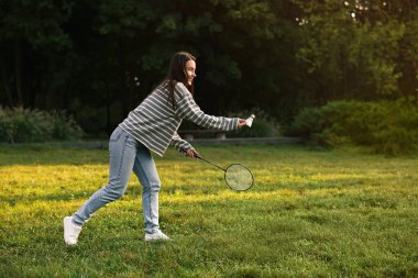 Parkta badminton oynayan genç bir kadın.