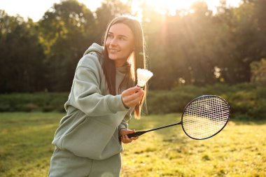 Güneşli bir günde parkta badminton oynayan mutlu genç bir kadın.