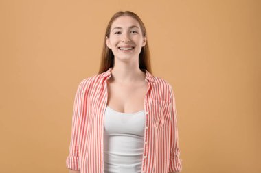 Bej arka planda diş telleri olan gülümseyen kız.