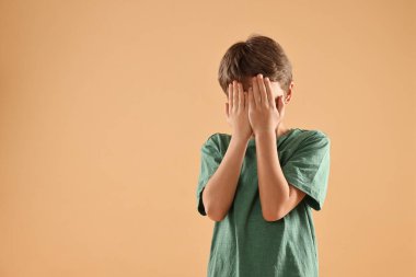 Bej arka planda elleri olan korkmuş küçük bir çocuk. Metin için boşluk