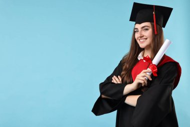 Mezuniyetten sonra açık mavi arka planda diplomalı mutlu bir öğrenci. Metin için boşluk