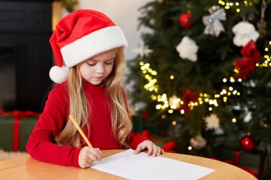 Küçük kız Noel Baba 'ya mektup yazıyor. Noel kutlaması