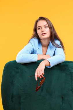 Fashion portrait of woman in light blue jacket on yellow background clipart