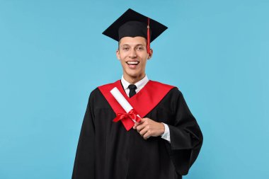 Mezuniyetten sonra açık mavi arka planda diplomalı mutlu bir öğrenci.