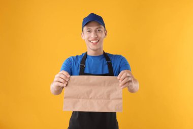 Turuncu arka planda kağıt torbası olan fast food işçisi.