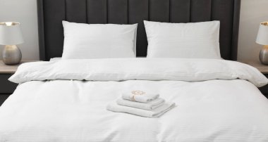 Temiz çarşafları, yastıkları ve havluları olan rahat bir yatak.