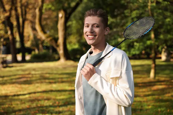 Parkta badminton raketiyle mutlu genç bir adam.