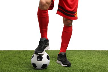 Beyazların arka planına karşı suni çimlerde futbol topu taşıyan futbolcu, yakın plan