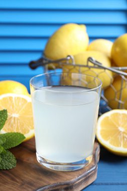 Bardakta taze meyve suyu, mavi ahşap masada limon ve nane, yakın plan.