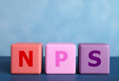 NPS (net tanıtımcı puanı) açık mavi arkaplana karşı tahta küplerden yapılan kısaltma