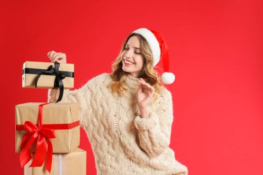 Kırmızı arka planda Noel Baba şapkalı güzel bir kadın.