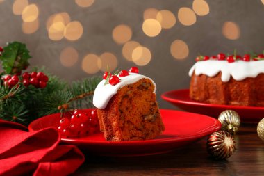 Bulanık ışıklara karşı geleneksel Noel pastası ve ahşap masanın üzerindeki dekor.