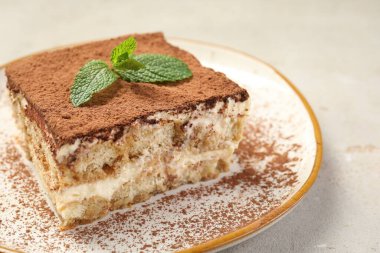 Lezzetli bir tiramisu. Bej masa üzerinde taze nane, yakın plan.