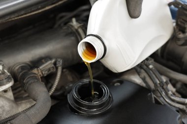 Otomobil motoruna motor yağı döken adam, yakın plan.