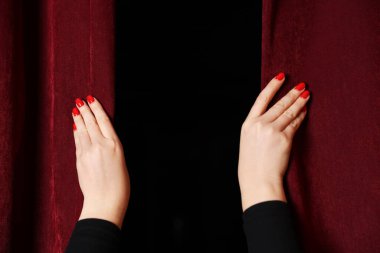 Tiyatroda kırmızı perdeleri açan kadın, yakın plan.