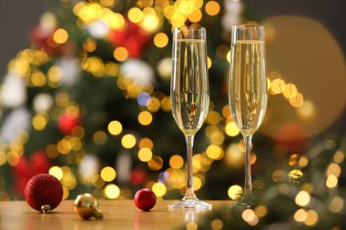 Şampanya bardaklar içinde ve ahşap masada bulanık Noel ışıklarına karşı şenlikli süsler, yazı için yer. Bokeh etkisi
