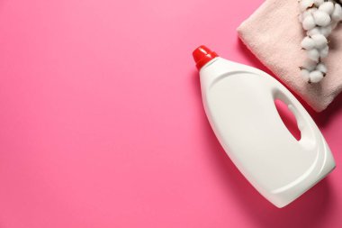 Çamaşır deterjanı şişesi, temiz havlu ve pembe arka planda pamuk çiçekleri. Metin için boşluk