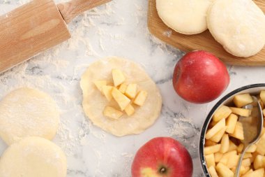 Pirozhki yapmak (doldurulmuş börek). Beyaz mermer masa üzerinde elmalı hamur parçaları, düz yatıyordu.