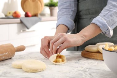 Beyaz mermer masada elmalı pirozhki yapan kadın, yakın plan.