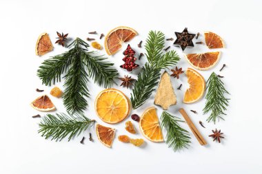 Farklı baharatlar, kurutulmuş portakal dilimleri ve beyaz masa üzerinde köknar ağacı dalları. Noel sezonu