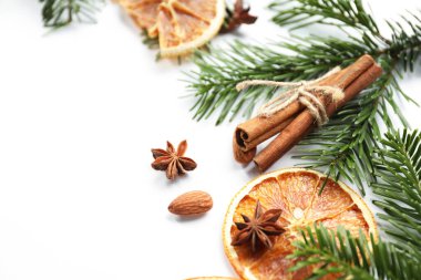 Farklı baharatlar, kurutulmuş portakal dilimleri ve beyaz masa üzerinde köknar ağacı dalları, yazı için yeri olan yakın plan. Noel sezonu