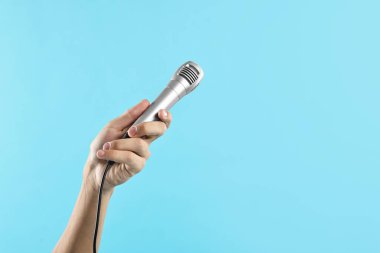 Açık mavi arka planda mikrofonu olan adam, yakın plan. Metin için boşluk