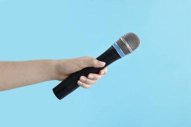 Açık mavi arka planda mikrofonu olan kadın, yakın plan.