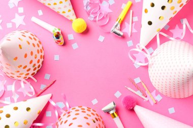 Pembe arka planda parti şapkaları, boynuzları, flamalar ve konfetilerden oluşan bir çerçeve. Metin için boşluk