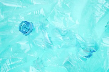 Turkuaz arka planda buruşmuş plastik şişeler, yakın plan.