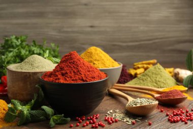 Ahşap arka planda farklı aromatik baharatlar ve otlar, yakın plan.