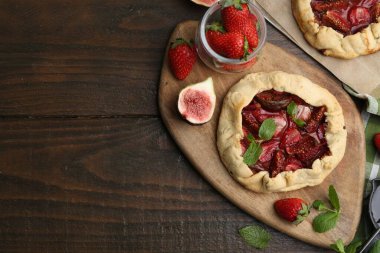 Çilekli lezzetli galetler, incir ve nane şekerli ahşap masa, düz yatak. Metin için boşluk