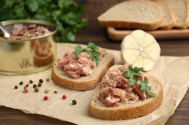 Konserve et, maydanoz, sarımsak ve biberli sandviçler ahşap masada, yakın plan.