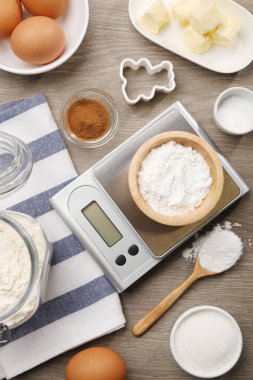 Mutfak terazisi kabartma tozu ve diğer ürünlerle ahşap masa, düz yatıyordu.