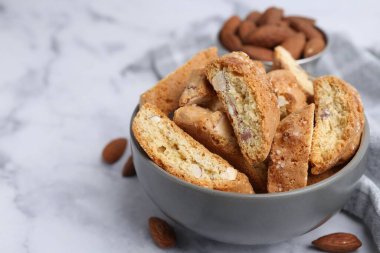 Lezzetli bademli bisküviler (Cantuccini) kasede ve fındıklar hafif mermer masada, yakın plan. Metin için boşluk