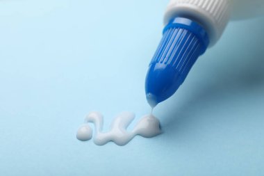 Açık mavi arka planda şişeden yapıştırıcı sürüyorum, yakın plan. Metin için boşluk