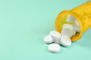 Sarı arka planda antibiyotik hapları olan bir ilaç şişesi, yakın plan. Metin için boşluk