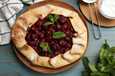 Kirazlı, nane ve pudra şekerli leziz galette açık mavi ahşap masa, düz uzanmış
