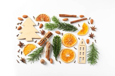 Farklı baharatlar, kurutulmuş portakal dilimleri ve beyaz masa üzerinde köknar ağacı dalları. Noel sezonu
