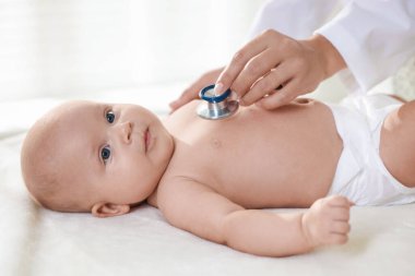Pediyatrist, klinikte steteskoplu küçük bir çocuğu muayene ediyor. Bebeğin sağlığını kontrol ediyorum.