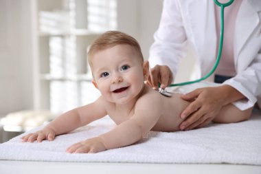 Pediyatrist, klinikte steteskoplu küçük bir çocuğu muayene ediyor. Bebeğin sağlığını kontrol ediyorum.