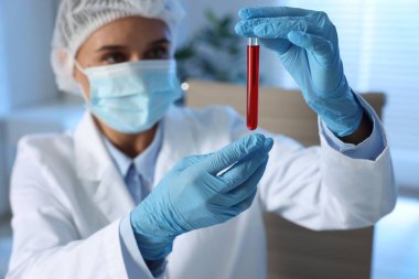 Laboratuvar testi. Kapalı alanda kan örneği olan test tüpü tutan doktor, seçici odaklanma