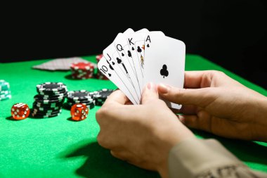 Poker oyunu. Yeşil masada iskambil oynayan kadın, yakın plan.