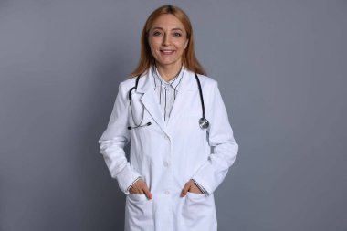 Gri arka planda steteskobu olan gülümseyen doktor.