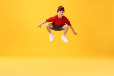 Mutlu küçük çocuk sarı arka planda zıplıyor