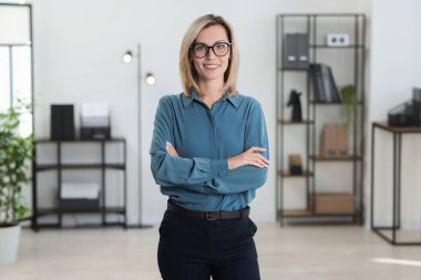 Ofiste kollarını kavuşturmuş mutlu bir iş kadını portresi.