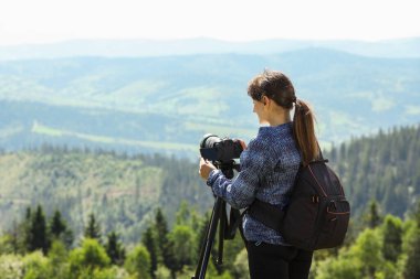 Sırt çantalı ve kameralı bir fotoğrafçı güzel dağların fotoğrafını çekiyor. Metin için boşluk
